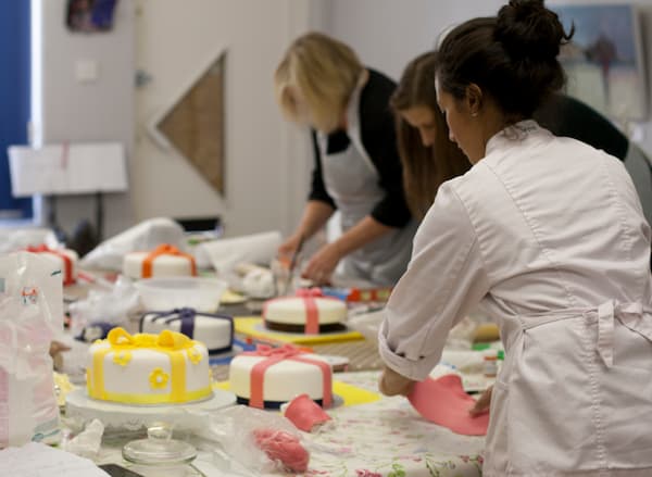 a baking experience event showing participants and a table of cakes in progress