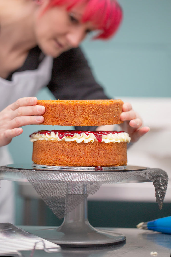 A cake experience participant building a 2 layered sponge cake